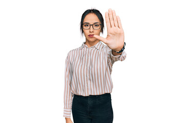 Young hispanic girl wearing casual clothes and glasses doing stop sing with palm of the hand. warning expression with negative and serious gesture on the face.