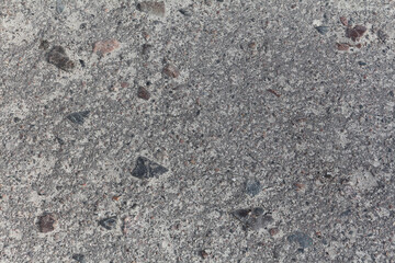 Fototapeta na wymiar Old asphalt road with smal stones close up. Grey grunge background with detailed organic texture.