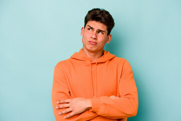 Young caucasian man isolated on blue background dreaming of achieving goals and purposes