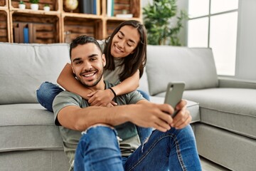 Obraz premium Young latin couple smiling happy making selfie by the smartphone at home.
