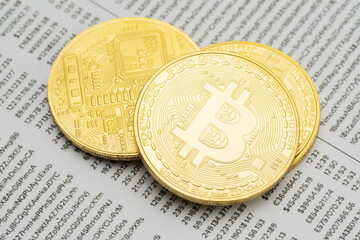 Close-up of three physical golden Bitcoin cryptocurrency coins on a mockup blockchain transactions list