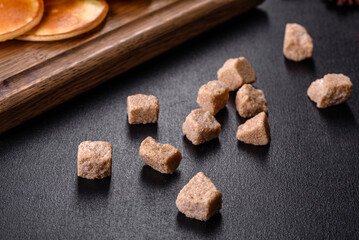 Brown unrefined cane sugar cubes on dark background