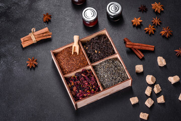 Several kinds of dry black tea with bergamot, rooibos, green and frame in a wooden box on a black concrete background