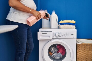 Middle age hispanic woman pouring detergent at laundry room