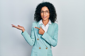 Young latin girl wearing business clothes and glasses amazed and smiling to the camera while...