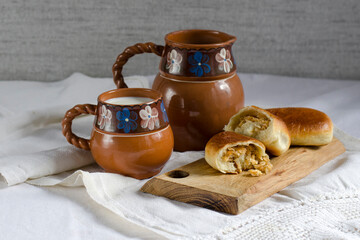 Homemade cabbage pies and a rustic-style ceramic jug of milk