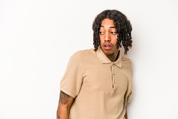 Young African American man isolated on white background looks aside smiling, cheerful and pleasant.