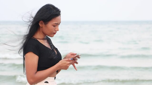 A young woman on a evening beach watch her smart phone