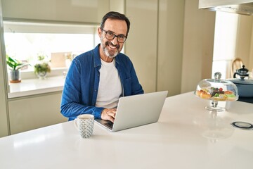Naklejka na ściany i meble Middle age man smiling confident using laptop at home