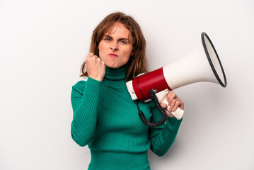 Young caucasian woman holding a megaphone isolated on white background showing fist to camera, aggressive facial expression.