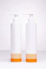 two white bottles for cosmetics with an orange pattern on a white background