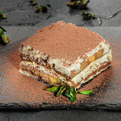 Traditional italian dessert tiramisu with mint on black board. Square image