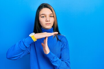 Young brunette girl wearing turtleneck sweater doing time out gesture with hands, frustrated and...