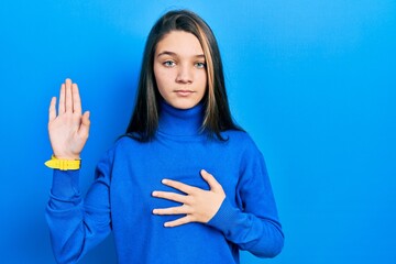 Young brunette girl wearing turtleneck sweater swearing with hand on chest and open palm, making a...