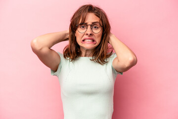 Young caucasian woman isolated on pink background screaming with rage.