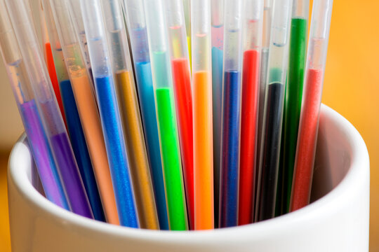Refills of a colored pens in the ceramic glassful close-up. Rainbow multicolor pattern.