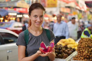 Tourist woman taste exotic fruit visit on asian market