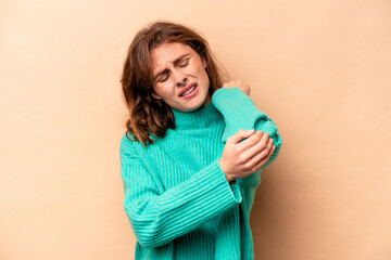 Young caucasian woman isolated on beige background massaging elbow, suffering after a bad movement.
