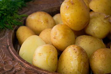 Delicious spring dinner - boiled young potatoes with butter and dill served in the wooden bowl
