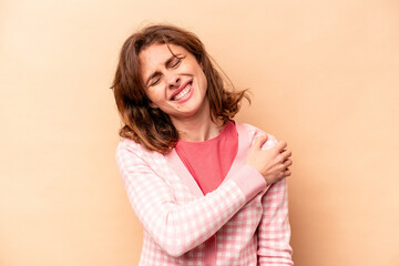 Young caucasian woman isolated on beige background having a shoulder pain.