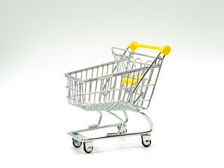 Small empty shopping cart on white and grey background. Selective focus.