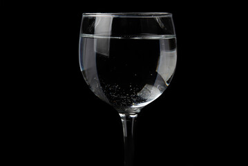 glass cup with white wine inside glass with water isolated on black background