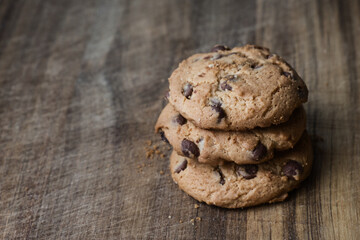 Delicious chocolate cookies on wooden table. Three biscuits with chocolate pieces in stack on wooden surface.