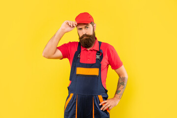 bearded man mechanic in work clothes on yellow background