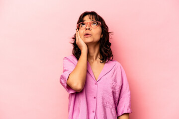 Young hispanic woman isolated on pink background tired and very sleepy keeping hand on head.