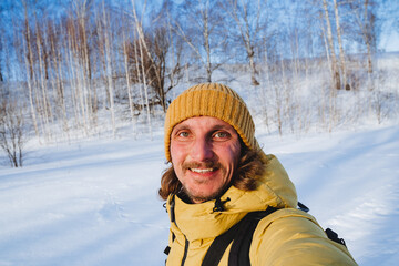 Hiking winter forest guy travels, yellow hat woolen, jacket warm, man smiling, cheerful man, laughter, handsome young man