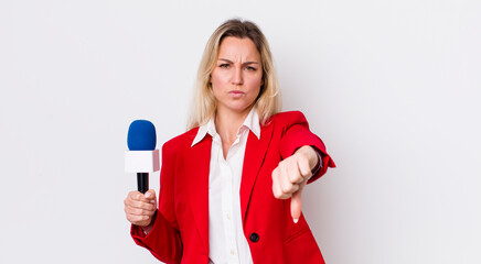 blonde pretty woman feeling cross,showing thumbs down. preporter and microphone concept