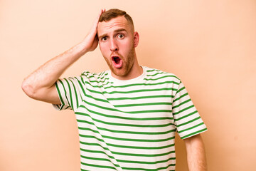 Young caucasian man isolated on beige background being shocked, she has remembered important...