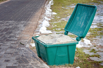 Grit salt bin. Container with rock salt mixture used in cold season to sprinkle sidewalks, ice...