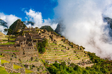 An overview of the ruins at Machu Picchu with clouds enveloping the mountain