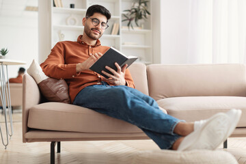 Smiling Arab man in glasses reading paper book