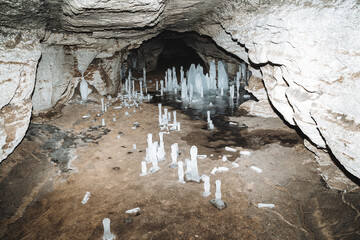 A cave underground ice stalagmites grow on the floor, a tunnel in the karst cavity of the mountain,...