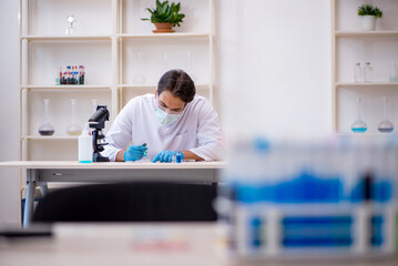 Obraz premium Young male chemist working at the lab