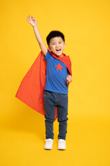 Smiling Superhero Asian boy in red cape isolated yellow background, Full body composition