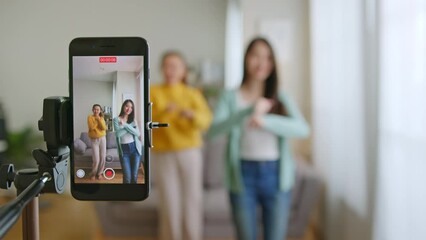 Asian young woman with her friend created her dancing video by smartphone camera together. To share video on tiktok social media application