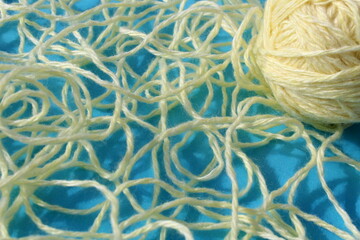 Threads of beige color with a ball lie on a blue background.