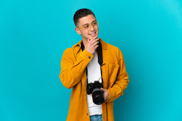 Young  caucasian photographer man isolated on blue background looking up while smiling