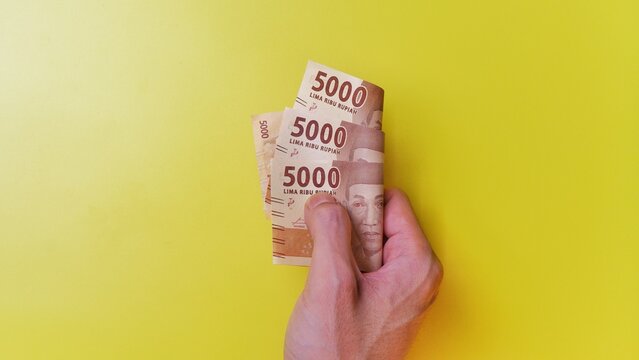 Indonesian Rupiah the official currency of Indonesia. Man's hand is making a payment. Business Saving Income Money Investment Economy and Finance Concept Uang 5000 5.000 Rupiah. Five thousand Rupiah.