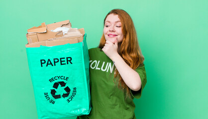 red head pretty woman smiling with a happy, confident expression with hand on chin. recycling...