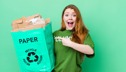 red head pretty woman looking excited and surprised pointing to the side. recycling concept