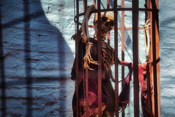 Fototapeta na wymiar A skeleton in a hanging cage wearing rags