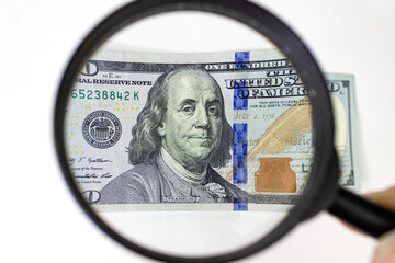 Finance and business. Closeup photo with a magnifying glass over 100 dollar banknotes.