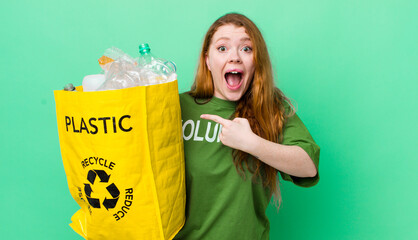 red head pretty woman looking excited and surprised pointing to the side. recycling concept