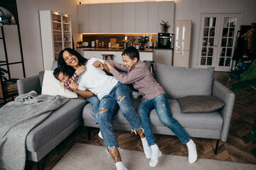 Happy african american family mom and two sons fooling around and having fun at home together