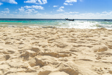 View of the sandy beach. On the horizon you can see the sea and silhouettes of boats. Seashore on a sunny day. Deserted sandy beach.