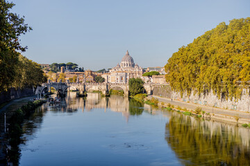 Landscape of Tiber river and green surroundings at sunny morning in Rome. Dome of famous saint Peter basalica on the skyline. Traveling Italy